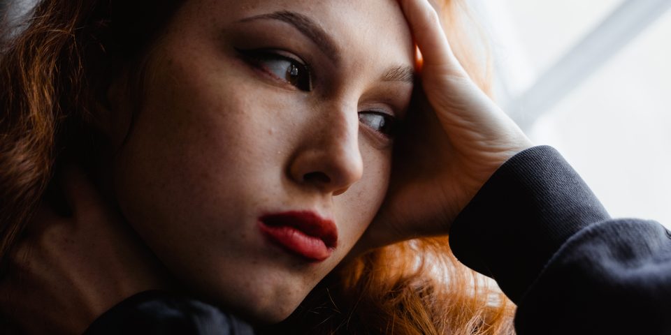 A woman resting her head on her hand, looking worried