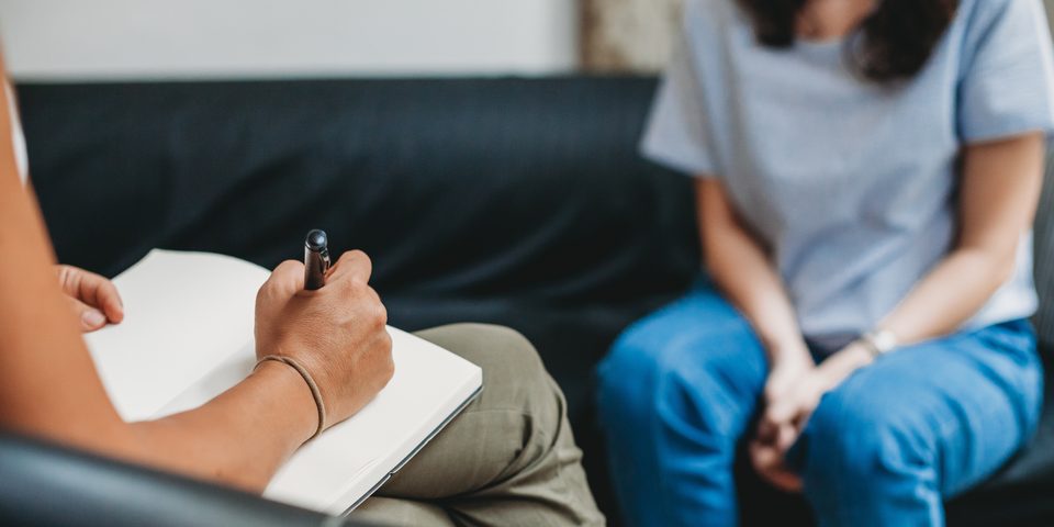 A counselor taking notes while talking with a client