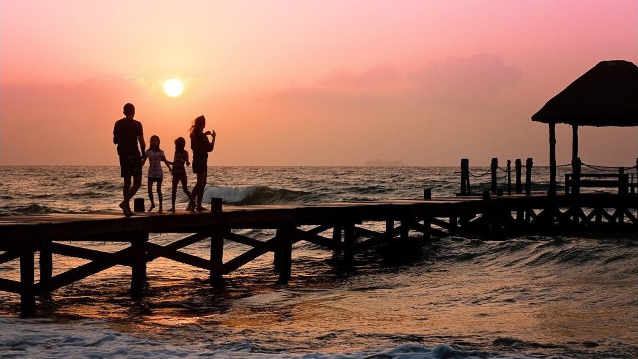 A family walking on a pier at sunset — still frame from the welcome video